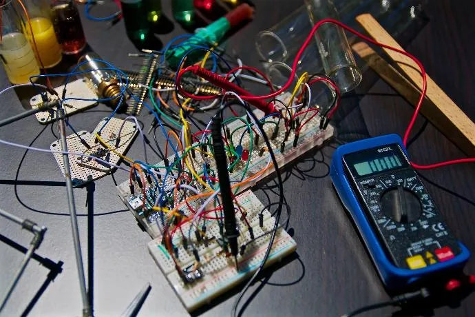 Placas de pruebas con circuitos electrónicos, cables y un multímetro