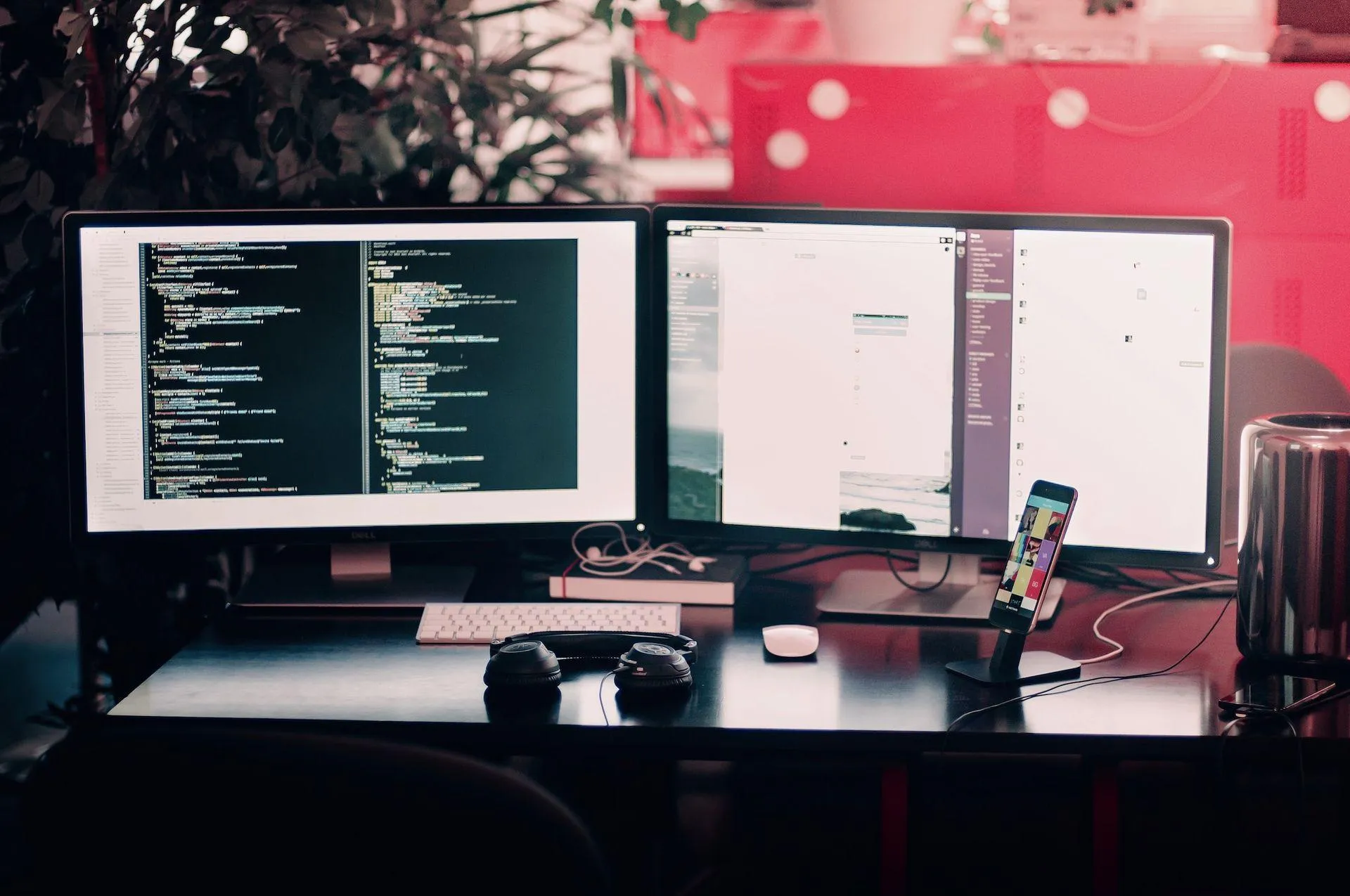Escritorio con dos monitores que muestran código y un teléfono móvil